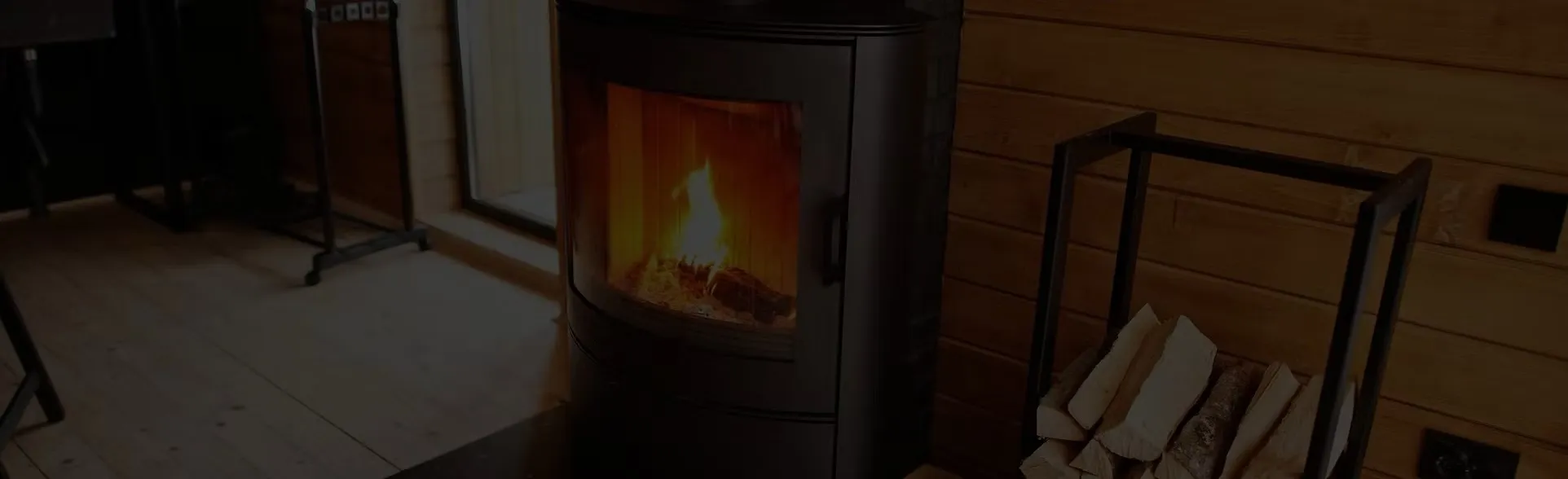 Ronde zwarte kachel met vuur, naast een rek met haardhout