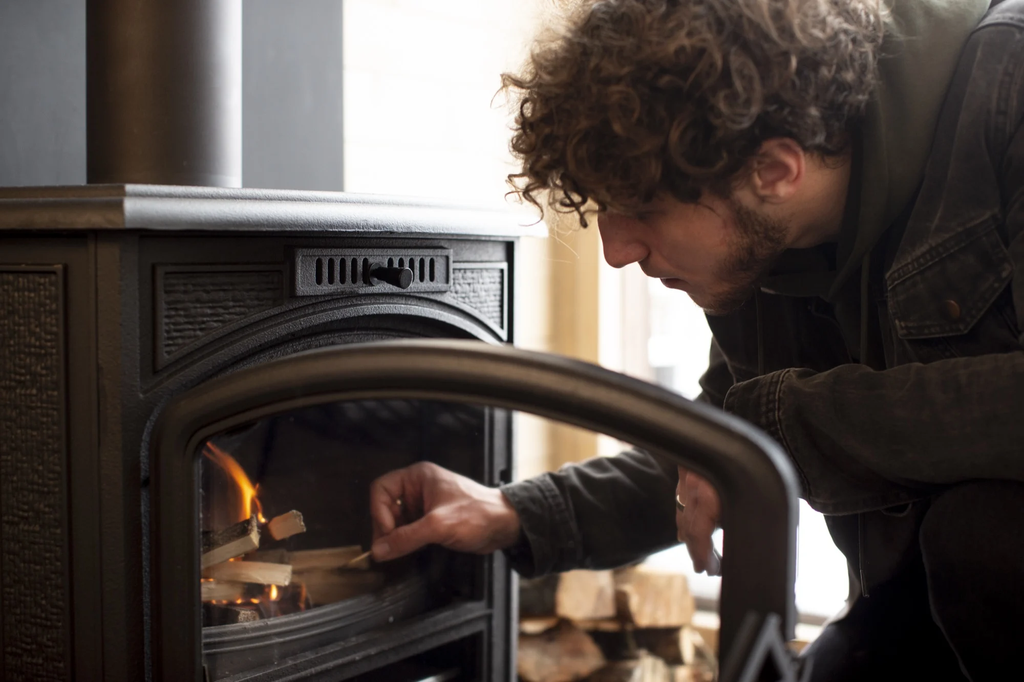 Man legt hout in een houtkachel