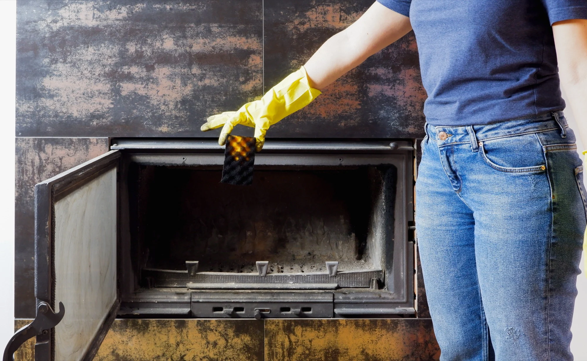 Iemand met handschoenen haalt as uit een houtkachel