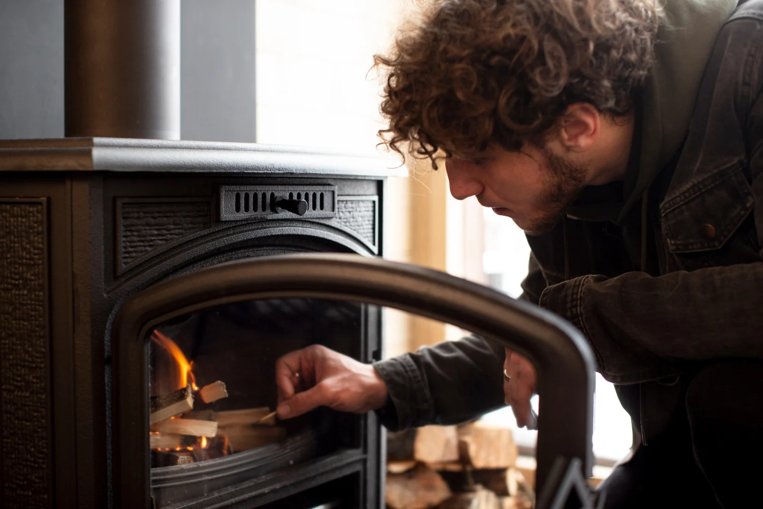 Man legt hout in een houtkachel