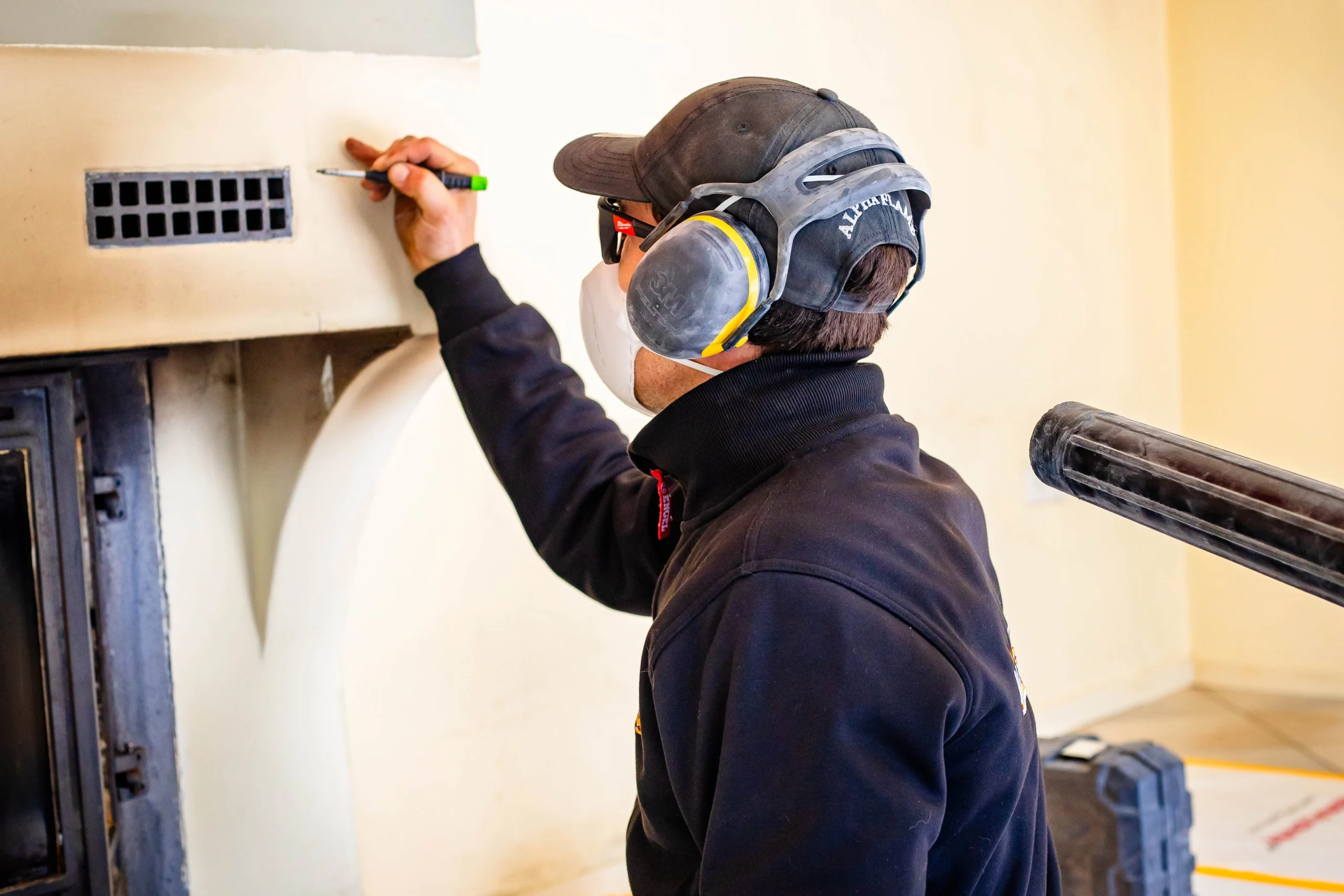 Monteur met stofmasker en gehoorbescherming tekent af op de schouw
