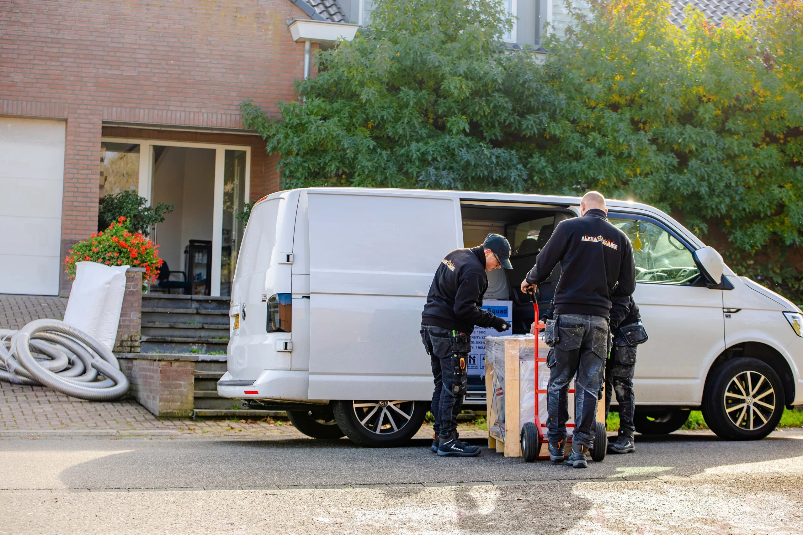 Monteurs bij de bedrijfsbus voor het huis, met een kachel op een steekwagen